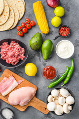 Wall Mural - Taco ingredients homemade  cooking with vegetables and chicken and pork meat on grey background top view.