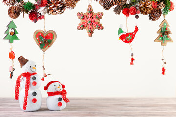 Poster - Winter festive concept with handmade snowman. Christmas or New Year decor with hanging garland of fir branches, red berries, pine cones and other wooden ornaments.