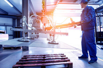 Worker uses suction cups for transporting large sheets of metal