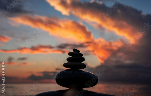pyramid or tower of pebble stones against the background of the sea and the sunset sky. Zen stones, balance and meditation concept