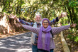 © luciano - Happy and content elderly hiker couple on the hike in the woods enjoying the freedom with arms outstretched. Two active retired seniors smile in an autumn landscape