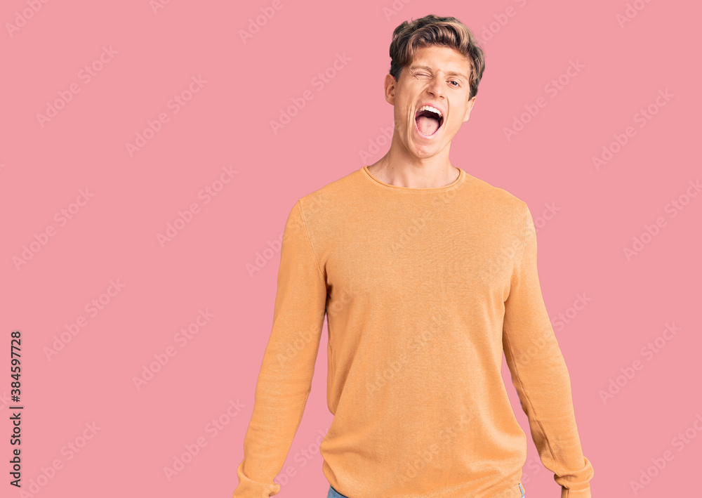 Young handsome man wearing casual clothes winking looking at the camera with sexy expression, cheerful and happy face.