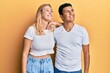 © Krakenimages.com - Young interracial couple wearing casual white tshirt looking away to side with smile on face, natural expression. laughing confident.