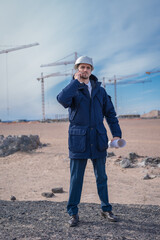 Wall Mural - a civil engineer in a white helmet is talking on the phone in the background of construction.