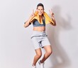 © Krakenimages.com - Young beautiful caucasian sportswoman wearing sportswear and towel smiling happy. Jumping with smile on face over isolated white background