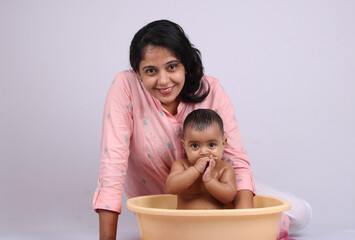 cheerful indian mother giving bath to baby.