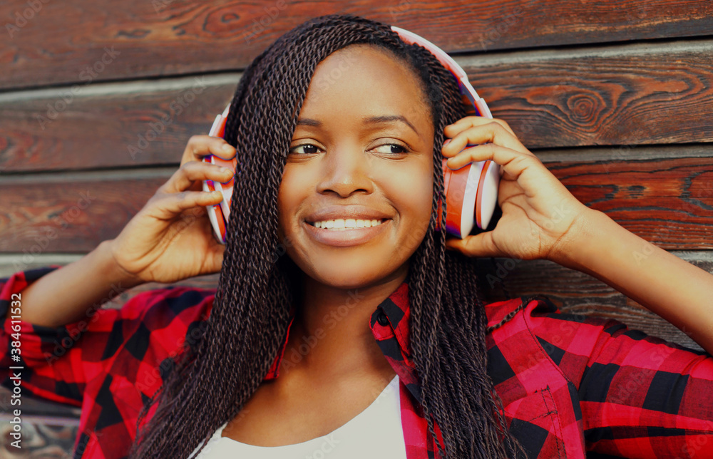 Portrait of happy young smiling african woman in wireless headphones ...