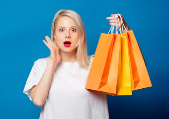 Canvas Print - Blonde in white t-shirt with shopping bags on blue background