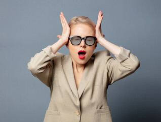 Poster - Blonde woman in jacket and glasses on gray background