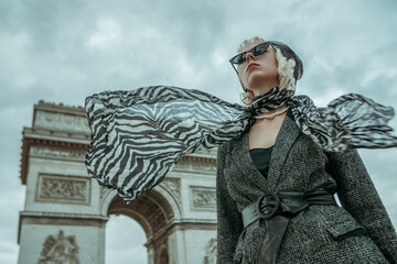 Outdoor autumn fashion portrait of elegant, luxury lady wearing trendy black boucle blazer, wide leather belt, animal, zebra print silk scarf, posing near Triumphal Arch in Paris. Copy, empty space