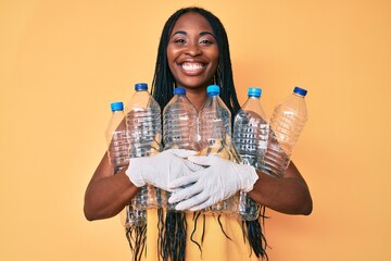 Canvas Print - African american woman with braids holding recycling plastic bottles smiling with a happy and cool smile on face. showing teeth.