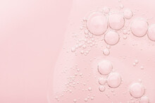 The Texture Of A Liquid Transparent Gel For Face Cleansing. Sample Of Oil Serum With Bubbles On A Pink Background. Moisturizing Cosmetic Beauty Product For Skincare. Lotion For Dry Skin Care