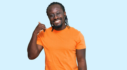 Sticker - Handsome young african american man wearing casual clothes smiling doing phone gesture with hand and fingers like talking on the telephone. communicating concepts.