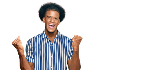 African american man with afro hair wearing casual clothes very happy and excited doing winner gesture with arms raised, smiling and screaming for success. celebration concept.