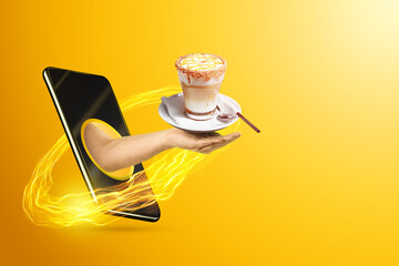 Hand serves cappuccino via smartphone on yellow background. The concept of food delivery, online ordering, restaurant services at home.