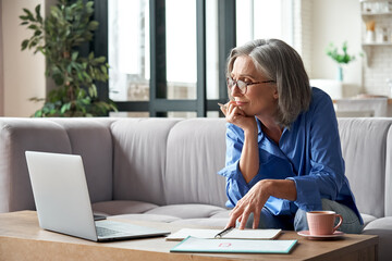 senior mature older woman watching business training, online webinar on laptop computer remote worki