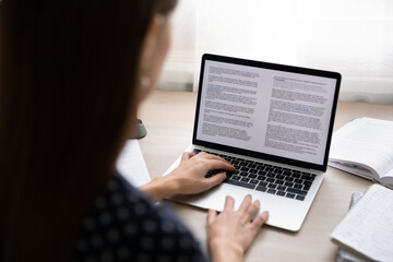 Back rear close up view focused young businesswoman working on electronic documents in computer editing application. Concentrated professional journalist writing article or student writing essay.