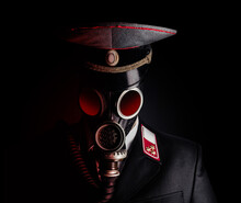 Portrait Photo Of A Post Apocalyptic Military Officer In Uniform Suit And Peaked Cap Standing In Soviet Gas Mask On Black Background.