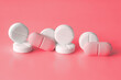 © LariBat - White and pink pills on a red background. Weight loss products, vitamins, hormones or sedatives, Women's health concept. Close-up, selective focus.