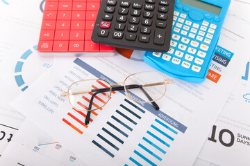 Wall Mural - Three calculators and a pair of glasses on financial documents