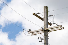 Top Of A Wood Utility Pole With Lines Against A Cloudy Blue Sky 