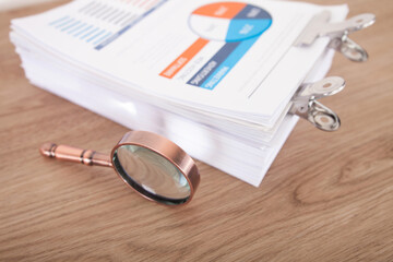 Wall Mural - A stack of paper documents and a magnifying glass on the table