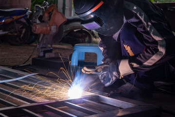 Wall Mural - The welder is welding the parts of the iron door. The person working on a welder using an electric welding machine.