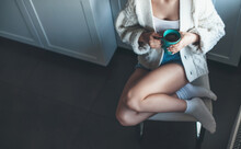 Caucasian Woman Sitting In A Chair In The Kitchen Drinking A Coffee Wearing A Knitter White Sweater