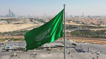 Wall Mural - Aerial view of Riyadh with the Kingdom of Saudi Arabia flag waving on the wind / 4K #1