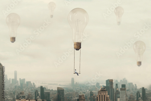Fotomural surreal moment of a woman traveling on a swing carried by a light bulb over a me