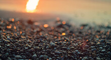Close-up View Of A Pebble Beach With Blurred Sea And Sun Background, Selective Focus