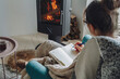 © perfectlab - Young woman  write in notebook sitting in armchair by fireplace