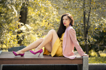 Autumn portrait of beautiful woman in yellow dress and pink blazer.