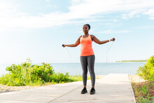 Fitness, Sport, Training, Park And Lifestyle Concept - African American Woman Exercising With Jump Rope On Beach