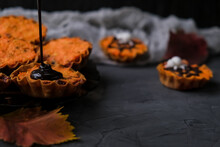 Orange Cupcakes In Tartlets With Spider On Background Of Gray Web. Chocolate Is Poured On Cake. Concept Of Halloween