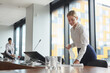 © Seventyfour - Portrait of smiling young woman cleaning table with sanitizing spray in conference room while preparing for business event in office, copy space
