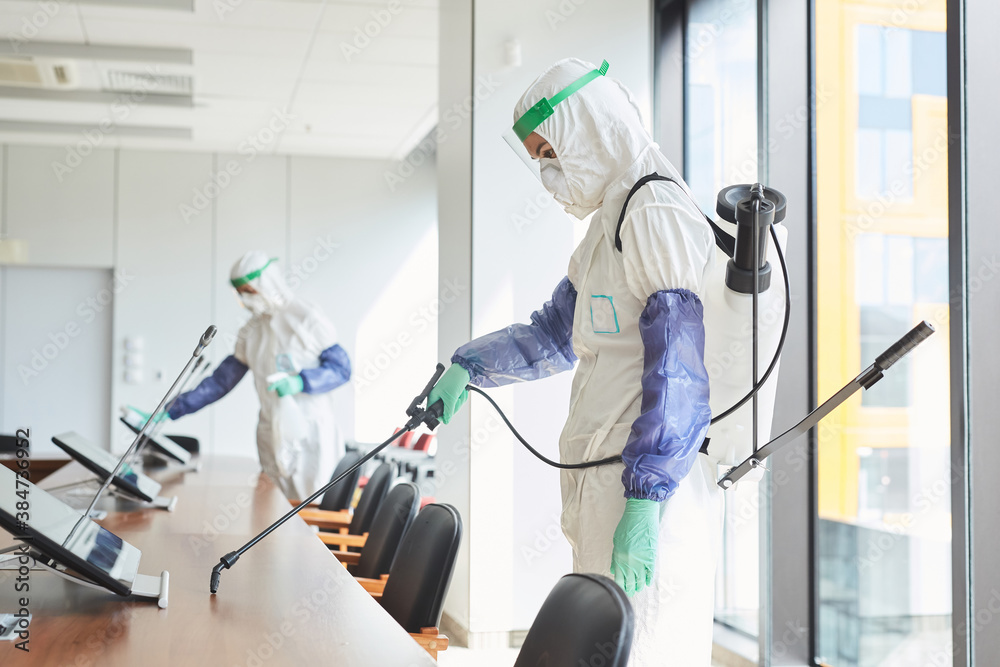 Side view portrait of two workers wearing hazmat suits disinfecting conference room in office, copy space - obrazy, fototapety, plakaty 