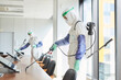 © Seventyfour - Side view portrait of two workers wearing hazmat suits disinfecting conference room in office, copy space