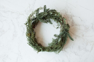 Wall Mural - Round wreath frame made of fir and eucalyptus branches on marble background. Christmas / New Year celebration decoration.