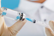 © Alexander - A doctor in rubber gloves holds an ampoule with a vaccine and a syringe, close-up.