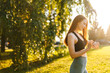 © dikushin - Side view of attractive young woman athlete using sport application on sport smart watch. Happy smiling lady wearing activewear preparing for morning or evening jogging background of sunlight outside.