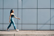 © GVS - Fashionable trendy african american woman walking along street wall urban background