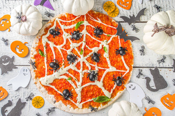 Halloween funny pizza. Halloween party recipe, Creative idea for Halloween pizza`s with ham and cheese ghosts, monster, spiders, white wooden background with Halloween decorations