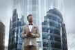Attractive black male businessman in a business suit against the backdrop of an office building.