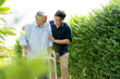 © NVB Stocker - Elderly Asian father and Adult son walking in backyard. Positive Asian man caregiver helping patient
