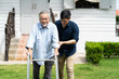 © NVB Stocker - Elderly Asian father and Adult son walking in backyard. Positive Asian man caregiver helping patient