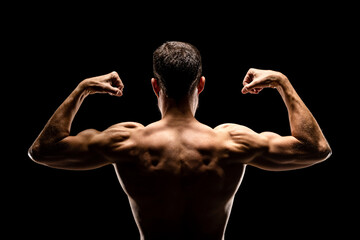 Wall Mural - Strong muscular man showing biceps back view, isolated on black background.