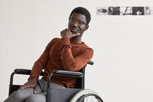 Minimal Portrait Of Young African-American Man Using Wheelchair And Looking At Camera While Posing In Modern Art Gallery, Copy Space