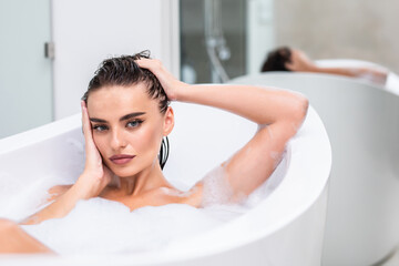 Wall Mural - Close up hot woman lying in foam at bathroom. Sexy woman relaxing at luxury bathtub.