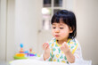 Baby eating bread. Asian baby girl enjoys a meal. baby-led weaning.